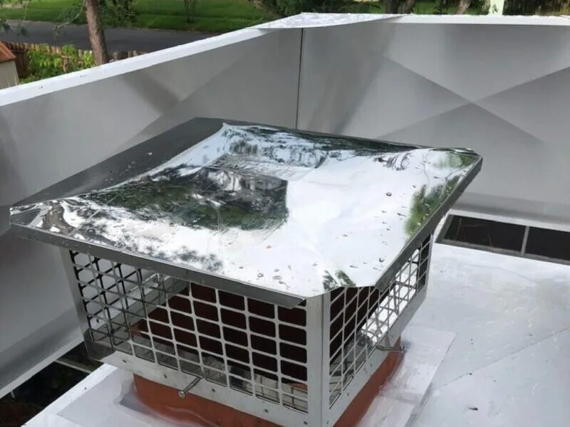 Stainless steel chimney cap installed on white stucco flat roof chimney in Lakeland, Florida