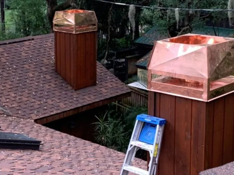 Copper chimney cap installation on cedar wood chimney surround with shingle roof