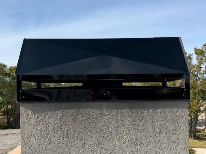 Galvanized black metal chimney cap installed on stucco chimney column