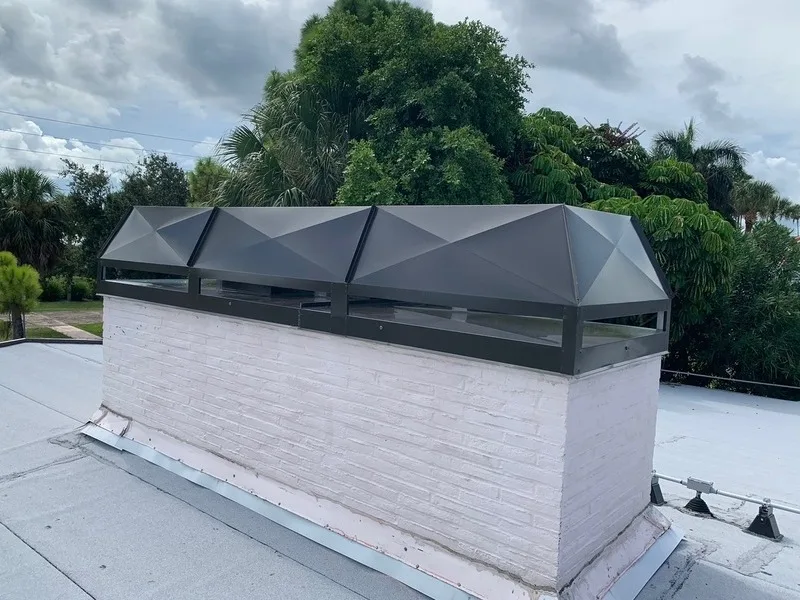 Stainless steel multi-flue chimney cap installed on painted brick chase