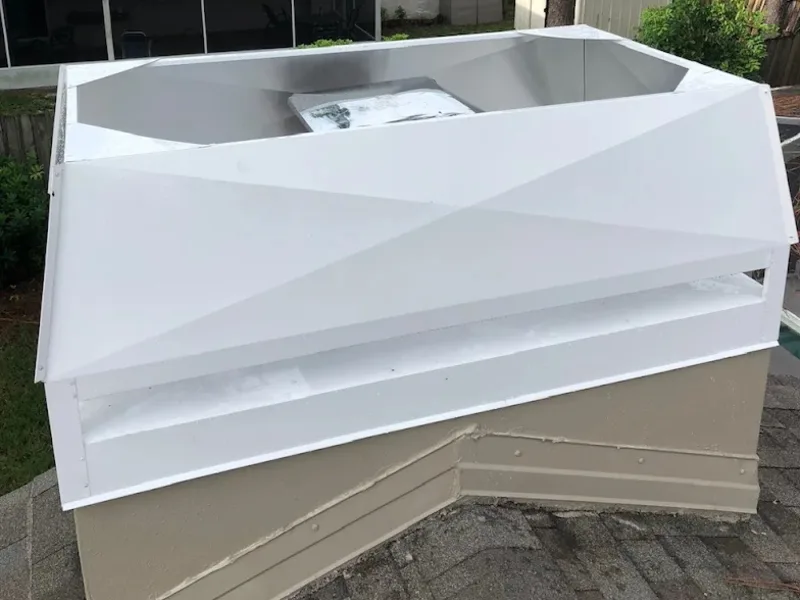 White galvanized chimney cap installed on stucco chimney with asphalt shingles